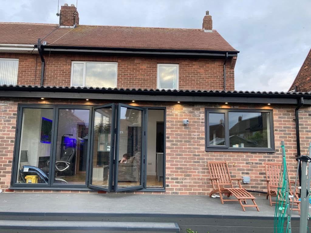 Rear view of the kitchen extension in Monkseaton, with anthracite bi-fold doors folded open and LED lights in the soffit