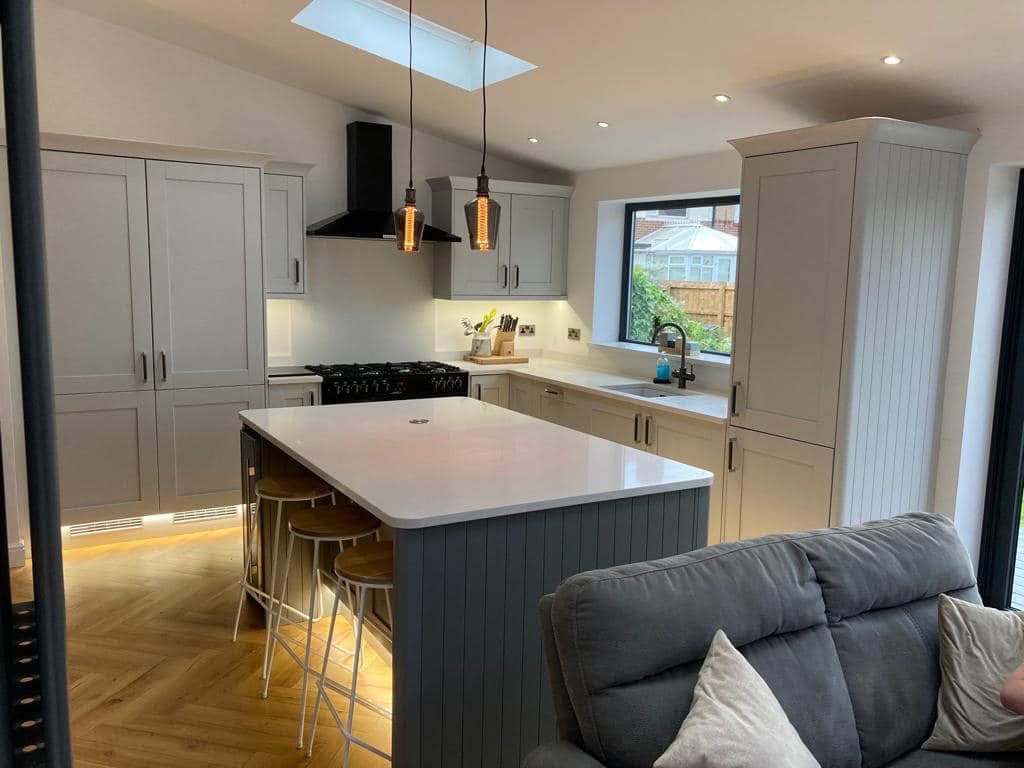 Kitchen extension in Monkseaton with pale grey shaker units, a range cooker and a panelled island seating three, under a roof light