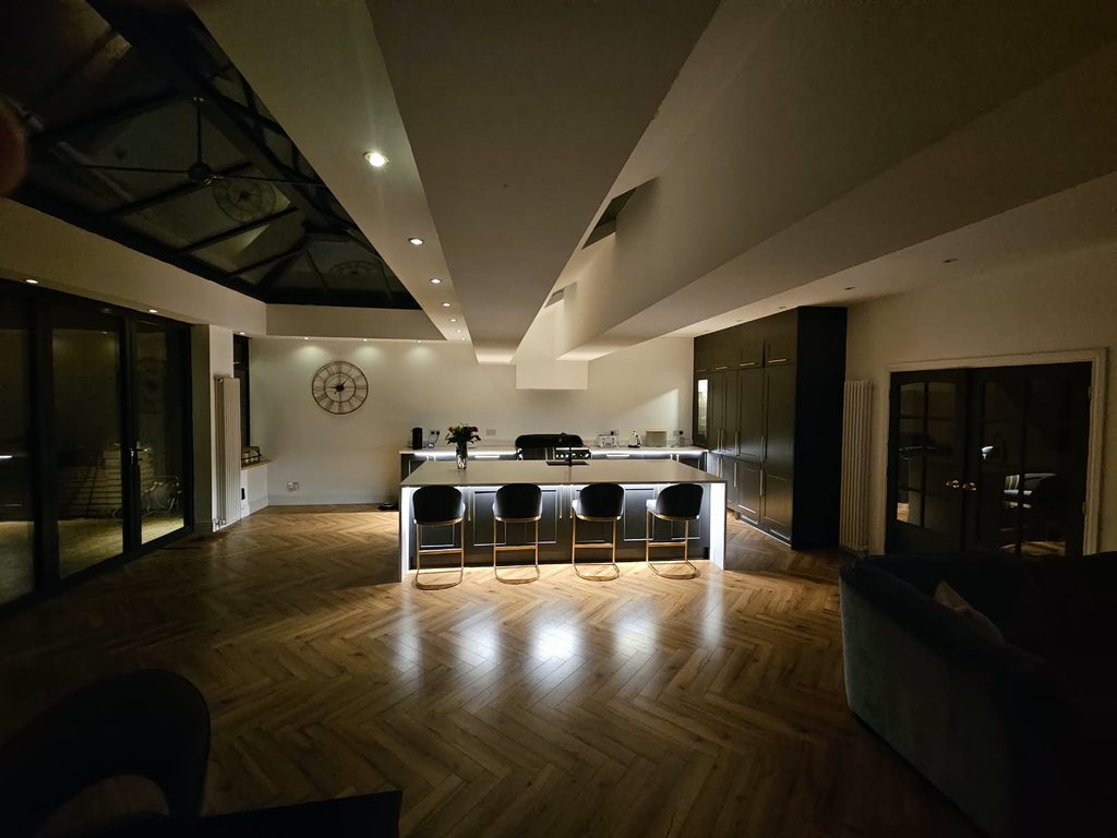 The open-plan kitchen at night, lit by LED strips under the island and base units