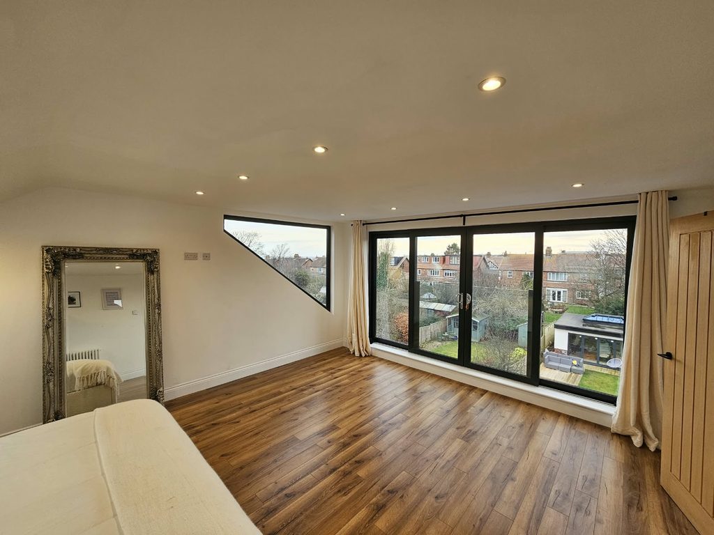 Loft master bedroom with full-height glazed doors, a glass Juliet balcony and an angled feature window