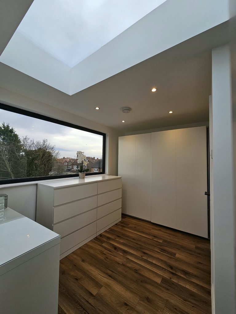 Loft dressing room with a wide black-framed picture window and a flat rooflight above