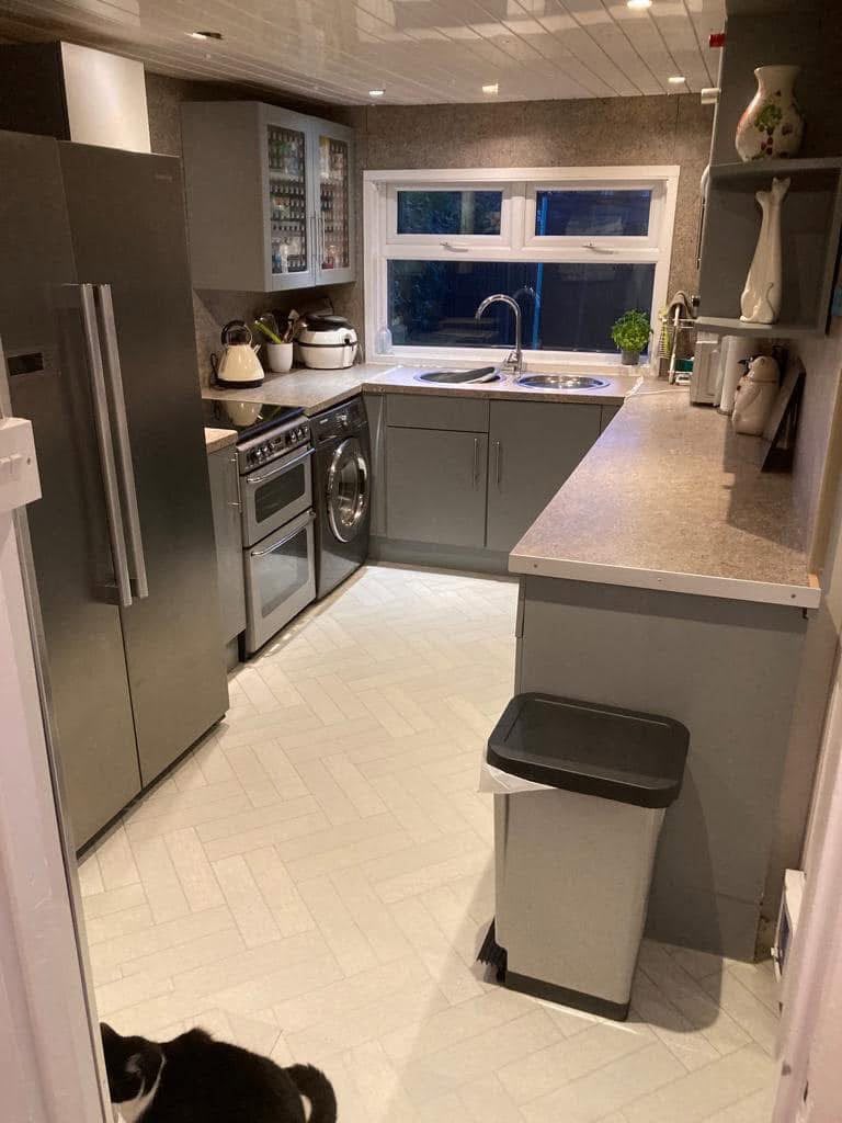 The original small kitchen, with grey units, laminate worktops and freestanding appliances