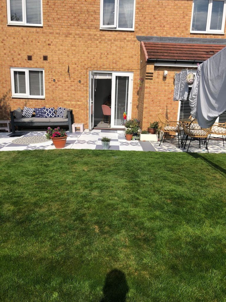 Rear of the house before the extension, with French doors, a red-tiled lean-to and a patterned patio