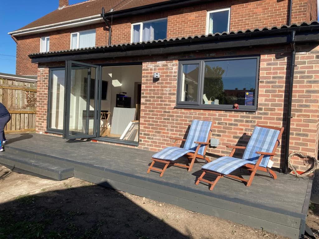 Red-brick single-storey rear extension with the bi-fold doors open and a wide window beside them