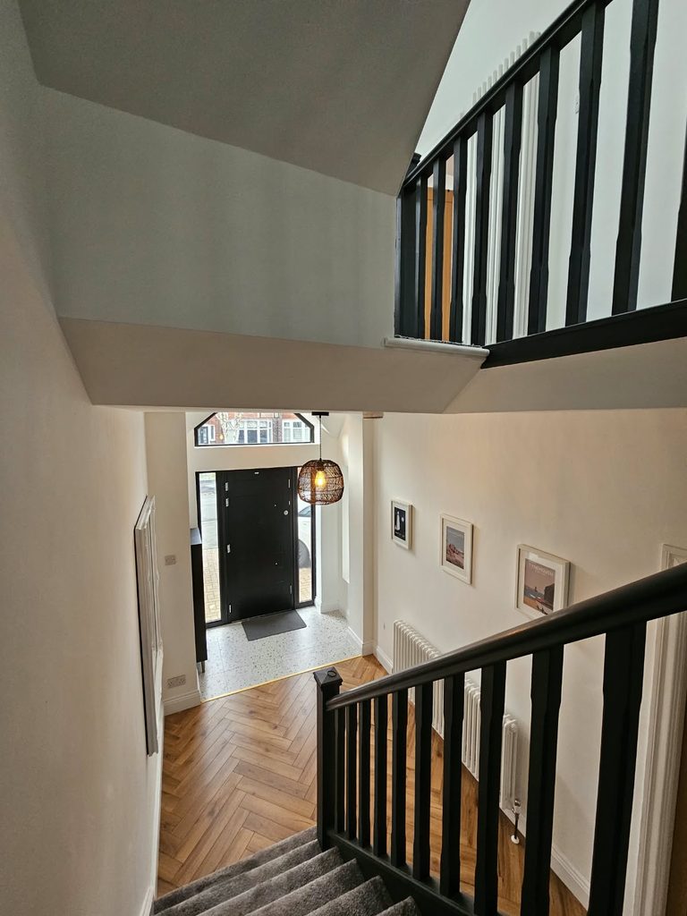 View down the staircase to the front door and glazed gable window