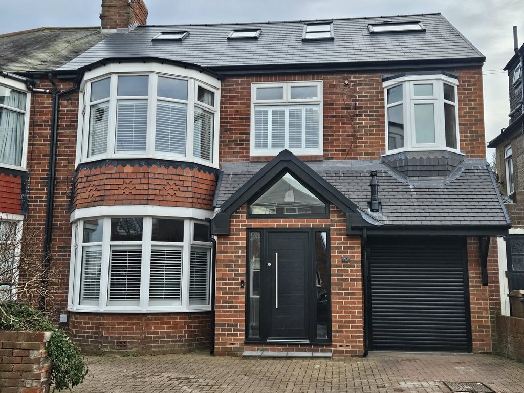 Front of the house after the two-storey side extension, with a gabled glazed porch, roller garage door and four rooflights