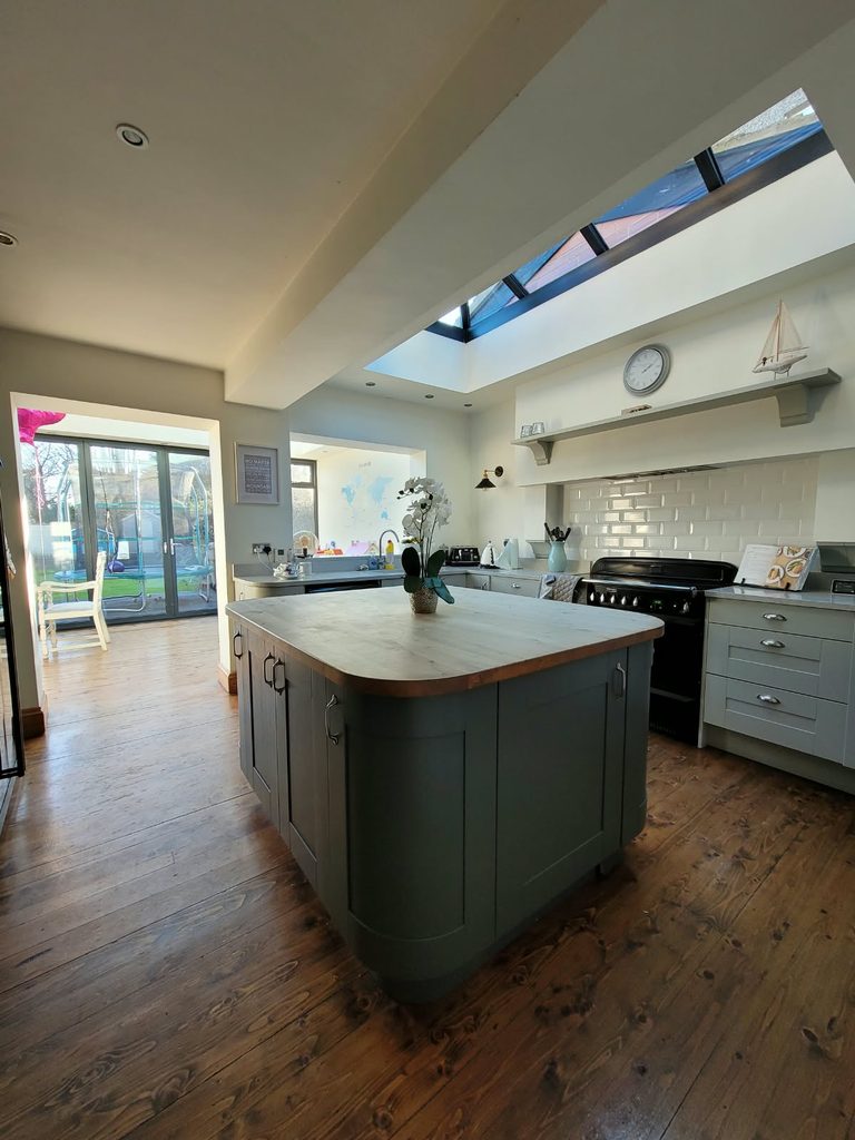 Original kitchen with sage shaker units and a wooden-topped island beneath the roof lantern, before the remodel